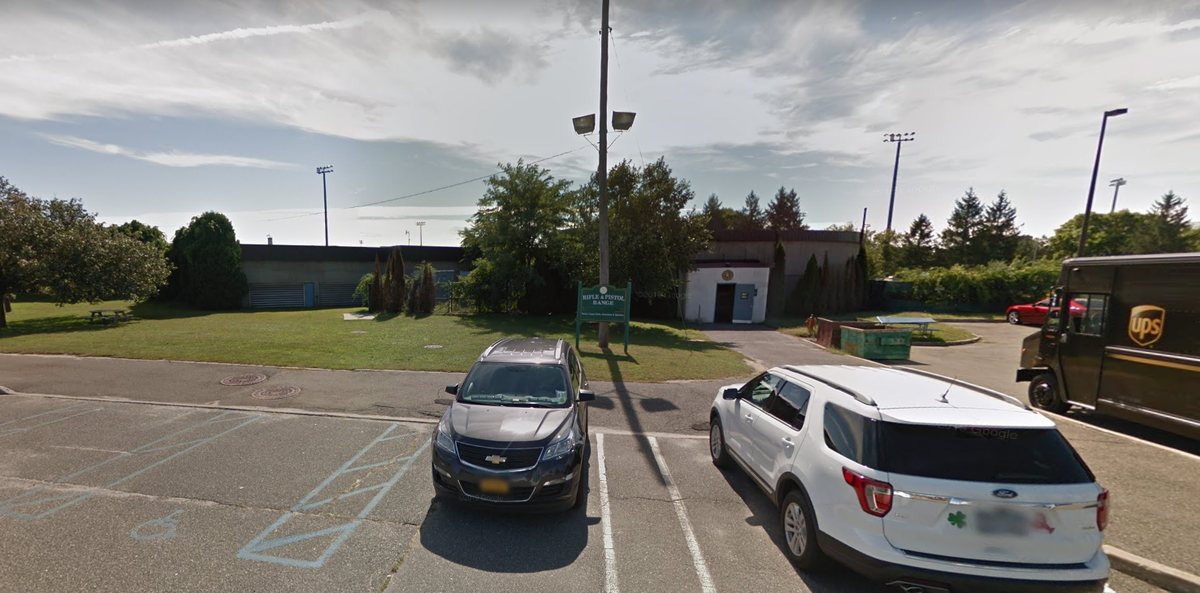 Front of the Rifle and Pistol Range building with the green range sign and the white entrance door on the right.